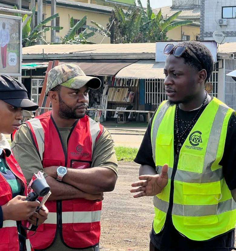 An instructor in hi-vis talking through an exercise with a student at the roadside in Douala